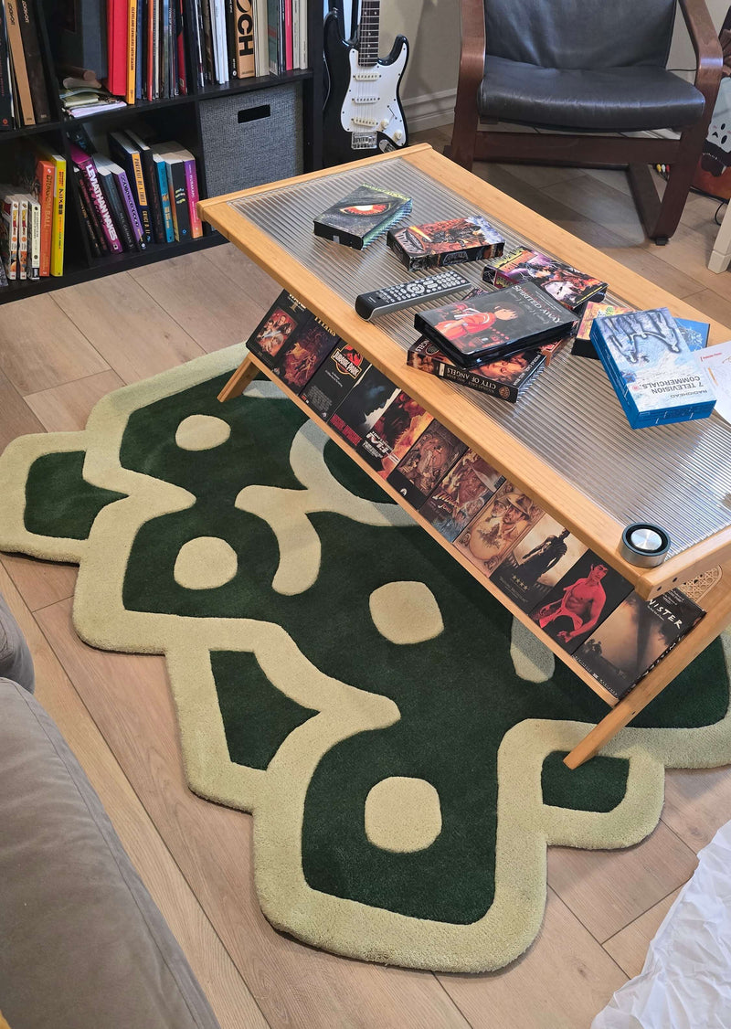 Living room with a coffee table, rug, and books on a wooden floor.